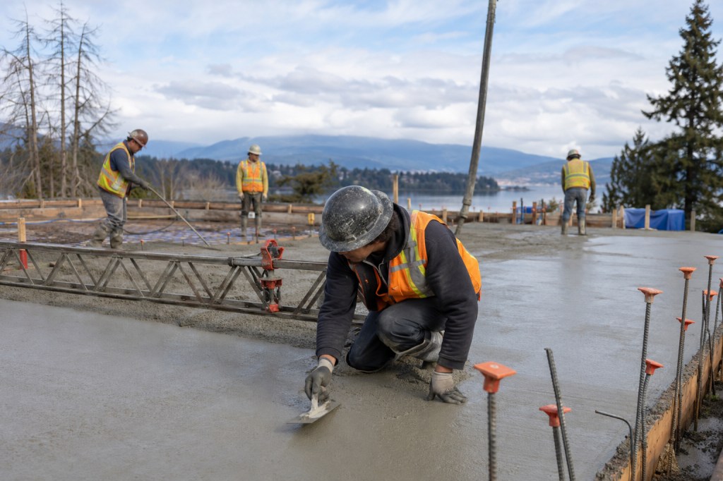 Concrete contractors placing and finishing a slab